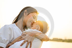 Loving mother holding and carrying her newborn baby with sunset view