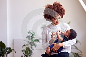 Loving Mother Holding Newborn Baby At Home In Loft Apartment