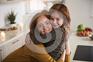 Loving mother hugging daughter at home