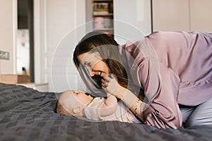 Loving mother looks at her baby lying on the bed