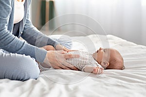 Loving Mother Making Belly Massage To Newborn Baby On Bed At Home