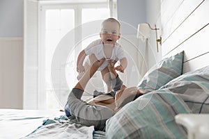 Loving mother play in bedroom with cute newborn