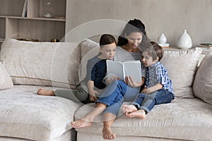 Loving mother reading book to little son and daughter