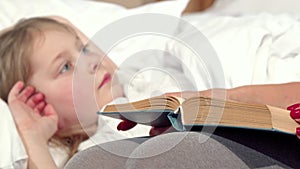 Loving mother reading fairytale to her daughter before sleep