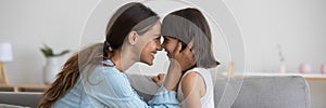Loving mother touching noses with adorable little daughter side view