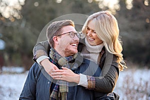 Loving Newly Engaged Couple Hugging On Snowy Walk In Winter Countryside