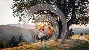 Loving newlyweds couple hugging in mountains at sunset. Groom holding bride on hands. Wedding in summer Carpathians.