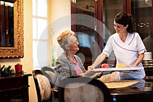 Loving nurse serving food to the occupants of the retirement home