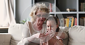 Loving older grandmother teaching little granddaughter knitting together