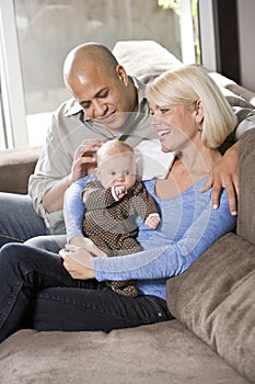 Loving parents with baby sitting on lap at home