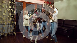 Loving parents and children dancing by Christmas tree at home