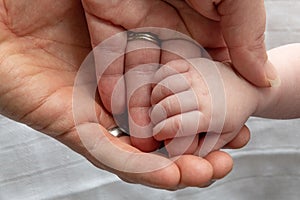 loving parents hands overlapping with their baby's hand holding their fingers