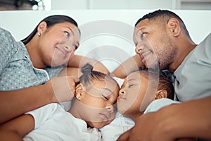 Loving parents looking at each other while cuddling with their two children. Little girl and boy sleeping in their