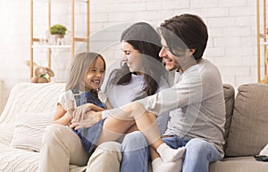 Loving parents tickling their little daughter, having fun together at home