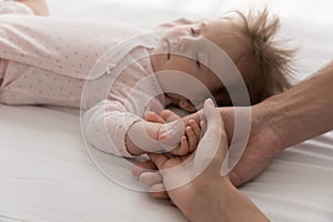 Loving parents touch tiny arm newborn sleeping baby, closeup shot