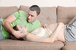 Loving pregnant couple hugs on bed in morning