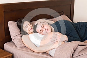 Loving pregnant couple hugs on bed in morning