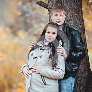 Loving pregnant couple walking in the autumn park