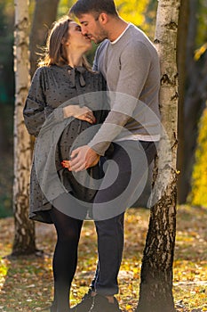 Loving pregnant young couple kissing tenderly.
