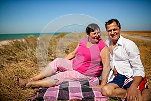 Loving Retired Couple Hugging Standing By Shore On Beach Vacation