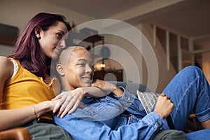 Loving Same Sex Female Couple Lying On Sofa At Home Watching TV And Relaxing Together