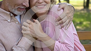 Loving senior couple embracing in park, comfortable retirement, secure old age