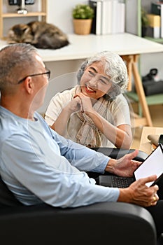 Loving senior couple having a conversation together while relaxing in cozy home. Elderly lifestyle and marriage concept