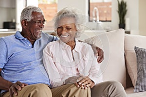 Loving Senior Couple Sitting On Sofa At Home And Laughing Together