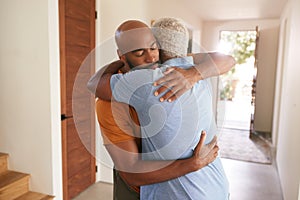 Loving Senior Father Hugging Adult Son Indoors At Home