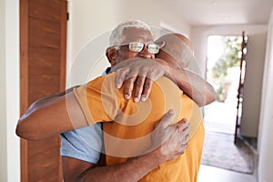 Loving Senior Father Hugging Adult Son Indoors At Home