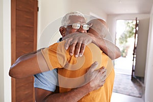 Loving Senior Father Hugging Adult Son Indoors At Home photo