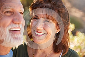 Loving Senior Hispanic Couple Hiking Along Trail In Countryside Together