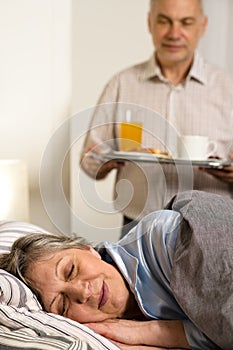 Loving senior husband serving breakfast to wife