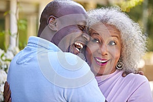 Loving Senior Retired Couple Hugging Outdoors In Garden At Home
