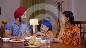 Loving Sikh family having lunch together in a dining room -  family love