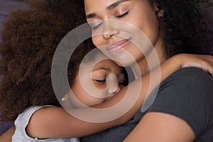 Loving single black mother hugs cute daughter feel tenderness connection photo