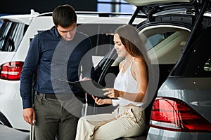 Loving smart couple choosing a car at the car dealership showroom