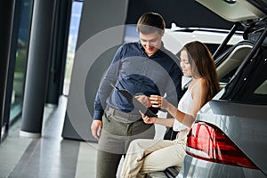 Loving smart couple choosing a car at the car dealership showroom