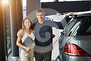 Loving smart couple choosing a car at the car dealership showroom