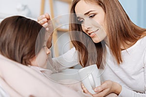 Loving smiling mother helping her sick daughter to recover