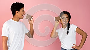 Loving teen couple talking through tin can phone