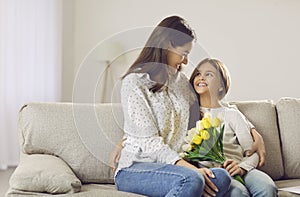 Loving teen girl congratulate mom presenting bouquet