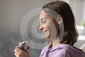 Loving teenage girl play with cite domesticated mouse at home photo