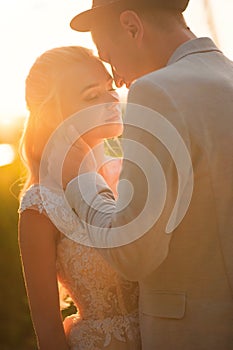 Loving wedding couple hugs and kisses in the summer at sunset. The concept of romantic relationship, idyll. Close-up kiss and tend