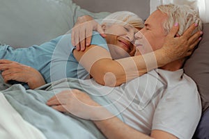 Loving wife tenderly hugging her spouse while lying with him