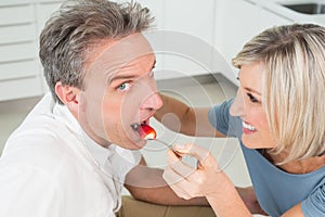 Loving woman feeding man in kitchen