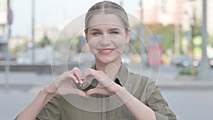 Loving Woman showing Heart Shape by Hands Outdoor