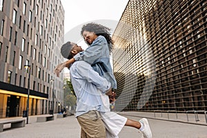 Loving young african couple enjoy each other walking outdoors during day.