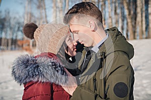 Loving young beautiful couple in the park on a bright sunny day. The guy and the girl are standing nose to nose and smiling