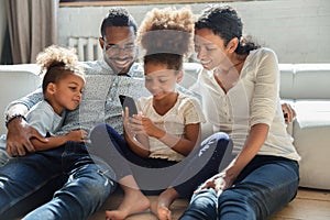 Loving young biracial family with kids using smartphone at home